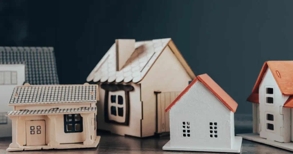 Dřevěné modely rodinných domů symbolizující nabídku a poptávku na realitním trhu