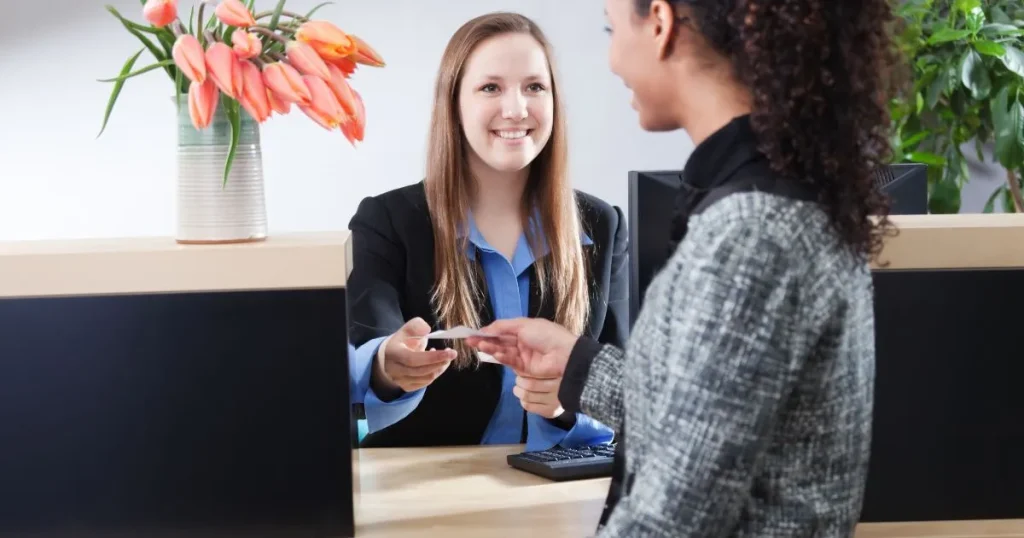 Usměvavá bankovní úřednice za přepážkou předává dokumenty klientce